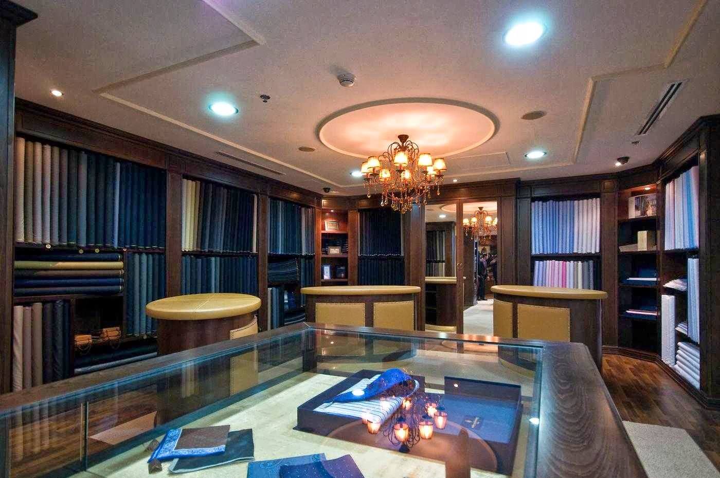 Inside Savile Row at Murjan 5: walnut cabinets stacked with suit cloth, a crystal chandelier and fitting counters