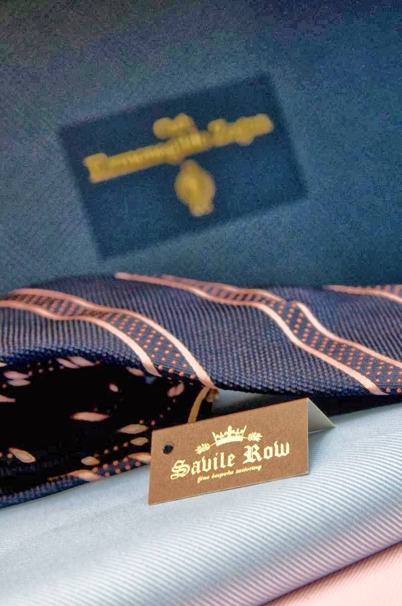 A bolt of suit cloth with its maker’s label beside a Savile Row tag